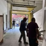 Espacio interior del local durante obra con trabajadores realizando tareas de construcción y remodelación